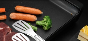 Détail d'une pince de cuisine ajourée en acier inoxydable pour griller la viande