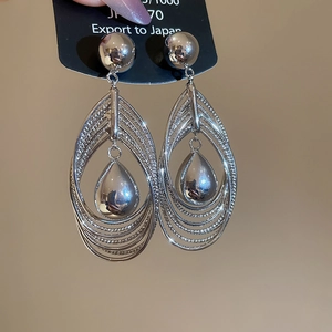 Macro detail of layered silver teardrop earrings with high-polish metallic finish
