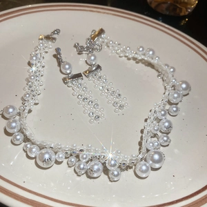 Detail of vintage pearl and rhinestone jewelry set with tassel earrings on a white plate