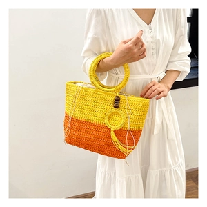 Straw tote bag detail with yellow orange gradient weave tassels and wooden beads