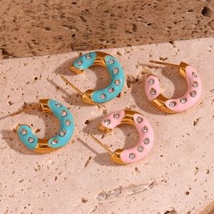 Detailed close-up of C-shaped 18K gold-plated enamel hoop earrings with sparkling rhinestones
