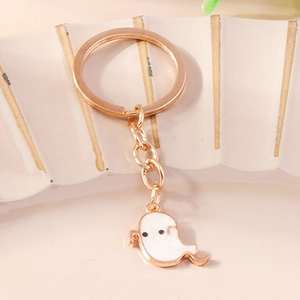 Close-up of cute white ghost charm keychain with gold metal ring and enamel finish