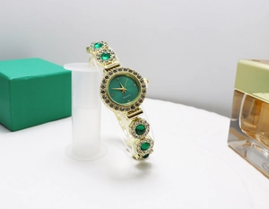 Detailed macro view of gold-toned quartz watch featuring green dial and inlaid rhinestones