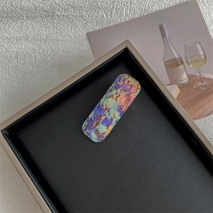 Detail of square vintage hair clip with colorful oil painting texture in a display tray