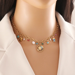 Golden necklace with elephant and fish pendants worn by a model in a white blazer