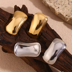 Detail of 18K gold and silver rectangular curved earrings on natural rock and wood