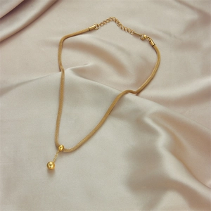 Elegant gold mesh chain necklace with spherical pendant on soft beige silk background