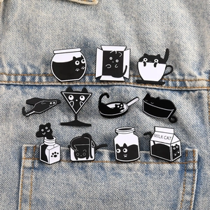 Set of 11 creative black and white cat enamel pins pinned on a blue denim jacket pocket