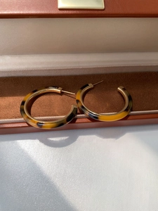 Close-up of tortoise shell resin C-shape earrings displayed in a brown leather jewelry box