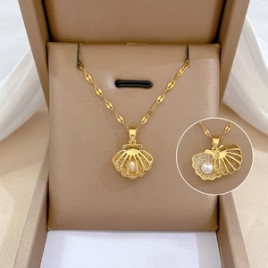 Detail view of gold shell pendant showing micro-set zircon and opening mechanism with pearl