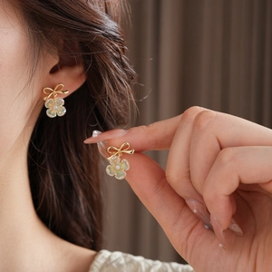 Detail of flower stud earrings with gold plating, pearl accent, and iridescent petals