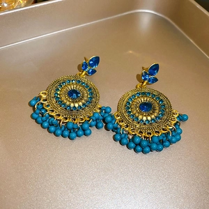Detailed shot of ethnic phoenix moon earrings with blue rhinestones and bead tassels