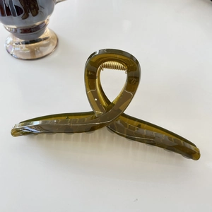 Detail of olive green translucent resin hair claw clip with a sleek crisscross loop design