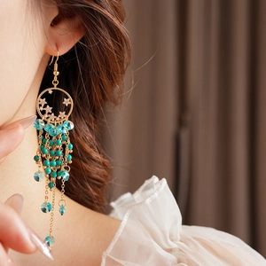 Détail d'une boucle d'oreille vintage dorée avec perles turquoise et cristaux sur modèle