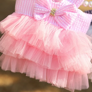 Detail of pink striped dog dress featuring a large bow with beads and tiered mesh skirt
