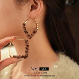 Golden geometric earrings with leopard print plush fur on model for winter fashion
