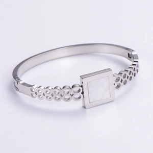 Macro detail of silver geometric bangle with square shell inlay and hollow chain design