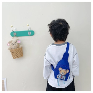 Rear view of a child wearing a blue cartoon bear chest bag with adjustable strap