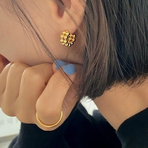 Nahaufnahme goldener Perlenohrringe und eines minimalistischen Rings am Model