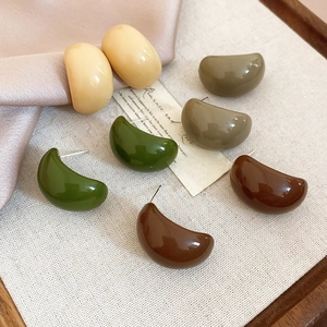 Detailed view of C-shaped acrylic earrings in cream, olive, and forest green tones