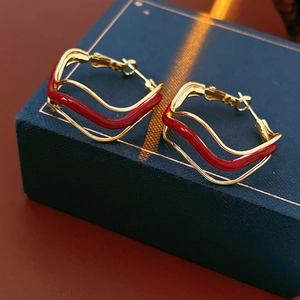 Detail of golden wavy hoop earrings with red enamel on a luxury jewelry box display
