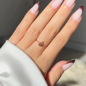 Gros plan d'une bague ajustable plaquée or 18k avec émeraude taille poire sur la main