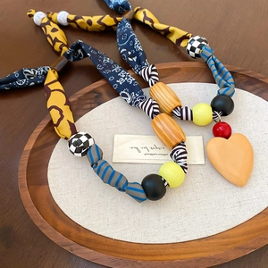 Détail du collier en tissu imprimé léopard avec des perles et un pendentif cœur