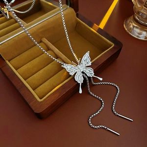 Detail of silver butterfly pendant necklace with long tassels on a velvet jewelry box