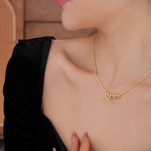 Dettaglio di una collana con ciondolo a serpente placcata in oro indossata con eleganza
