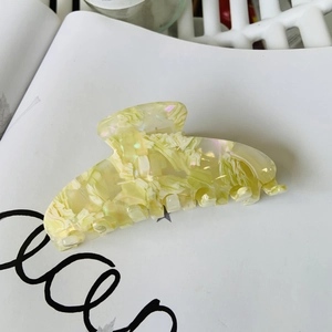 Close-up of large acetate hair claw clip with creamy marble pattern and pearlescent finish