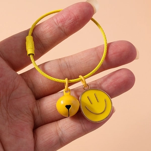 Close-up of a creative yellow metal keychain with smiley face pendant and bell