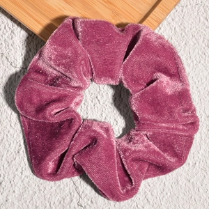 Detail of dark pink velvet scrunchie showing soft texture and glossy fabric ripples