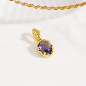 Detailed macro view of an 18k gold turtle pendant featuring a purple oval zircon stone