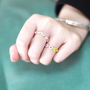 Close-up of colorful enamel chain rings with micro-set zircons on a model hand