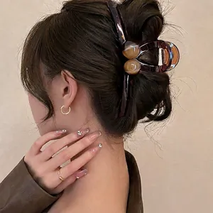 Large dark tortoiseshell hair claw clip for women shown on a model in a minimalist style