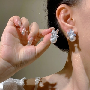 Detailed close-up of zircon-encrusted flower earrings with round white pearl drop pendant