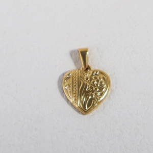 Macro view of a gold heart pendant with embossed floral patterns and a vintage finish