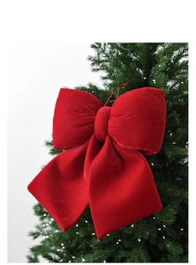 Large red velvet stuffed bow hanging on a Christmas tree for festive decoration