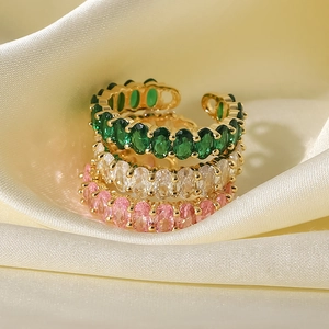 Close-up of three 18k gold plated adjustable rings with emerald, white, and pink zircons
