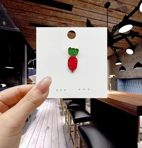 Dettaglio macro della spilla a carota in smalto con bordi dorati su carta