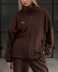 Close-up of brown fleece fabric texture and embroidered lettering on winter tracksuit