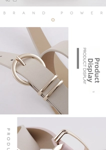 Détail d'une ceinture en cuir crème avec boucle ronde dorée et doubles passants métalliques