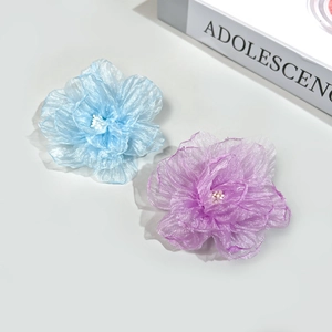 Détail de pinces à cheveux camélia en organza bleu et violet avec perle centrale