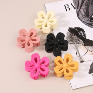 Flat lay of matte flower hair claws in cream, coral, black, rose, and orange colors