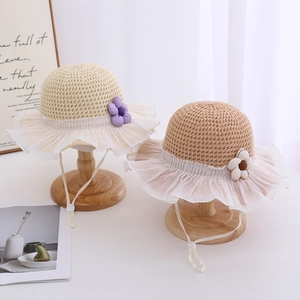 Girl's straw sun hat with elegant lace trim and fabric flowers on wooden stands