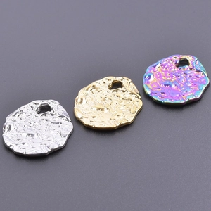 Macro shot of irregular lava-textured stainless steel pendants in silver, gold, and rainbow