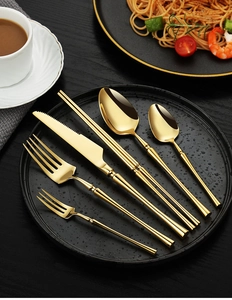 Close-up of luxury gold 304 stainless steel cutlery set on a black textured dinner plate