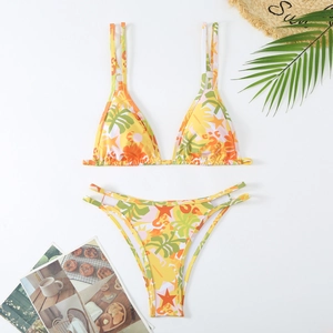 Flat lay of a two-piece tropical print bikini with palm leaves on white background