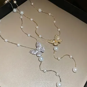 Halskette mit Schmetterling, Perlen und Quasten in Gold und Silber auf Display
