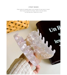 Detail of a pink tortoiseshell hair claw clip with a wave-shaped edge and metal spring
